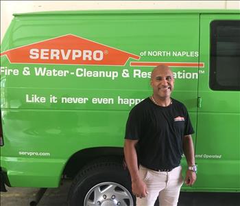 Guy posing for a photo in front of a green SERVPRO van.